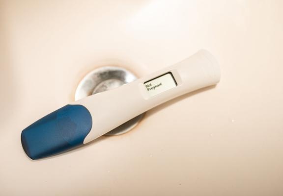 A pregnancy test sits in a bathroom sink and reads "Not Pregnant."