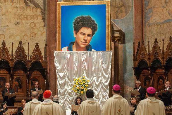 Priester vor einem Heiligenbild von Carlo Acutis