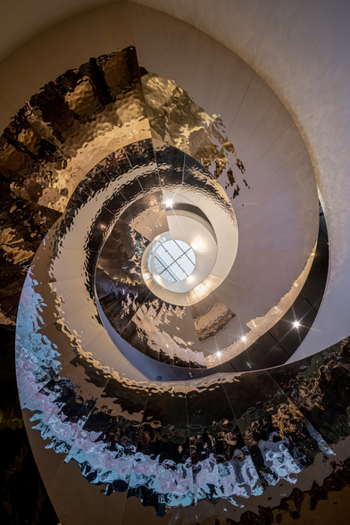 Der Blick nach oben in eine runde Treppe in glänzenden Gold. ￼