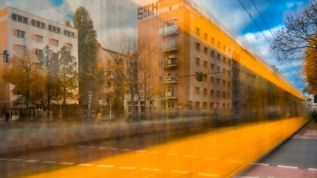 In einer verwischten Straßenbahn spiegeln sich die Häuser einer Straße