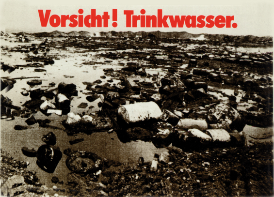 Ein S/W-Bild mit Fässern im flachen, schwarzen Wasser

Text: Vorsicht! Trinkwasser.