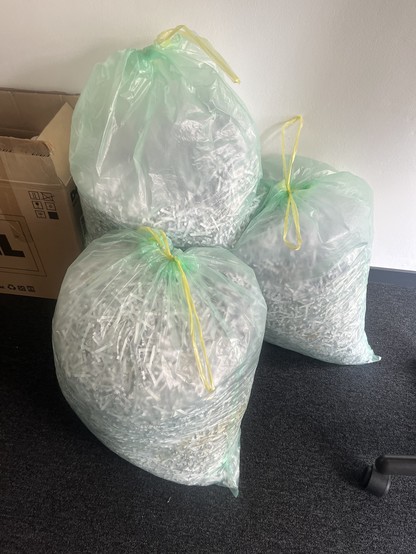 Multiple large trash bags filled with shredded paper.