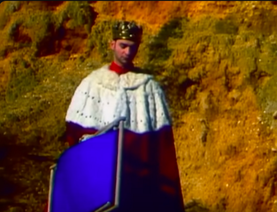 Dave Gahan with crown, king's robe and a deck chair.