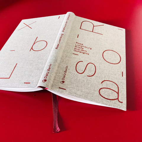 
Aufgeschlagen mit Lesebändchen: das Buch „Rosa Luxemburg — Briefe aus dem Gefängnis“ als in grobes Leinen gebundene Edition mit groß geprägten Lettern auf Cover und Rücktitel
