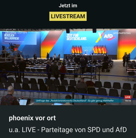 Screenshot der Phoenix App zeigt leere Reihen in der Halle des AfD Parteitages. Von hinten aufgenommen zeigt es vereinzelte Personen, viel schwarz Rotgold und leere Stühle 