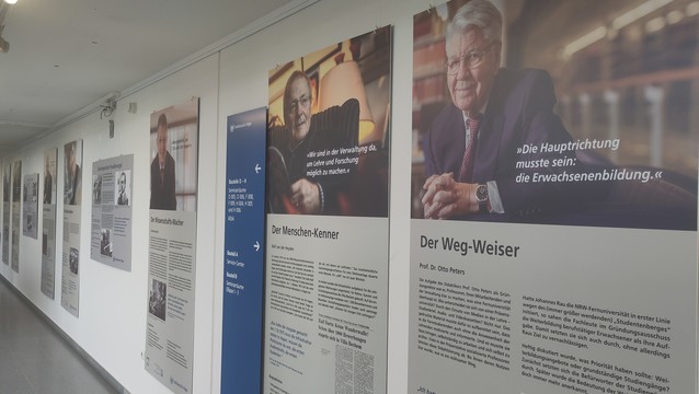 Fotowand mit großformatigen Bildern und Texten zu 40 Jahren Fernuni. Im Blick  eine Reihe von 8 Männern.