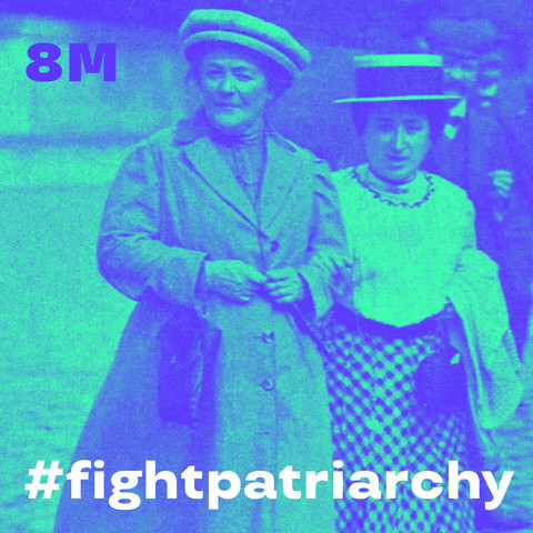 Eingefärbtes Foto von Clara Zetkin (links), die mit Rosa Luxemburg, bei ihr eingehakt, im Jahr 1910 voranschreitet. Oben steht 8M für 8. März, unten: #fightpatriarchy