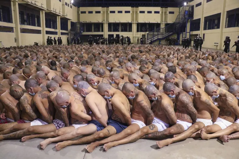 Innenhof eines Gefängnis. Hunderte von kahl geschorenen Männern nur in Unterhosen sitzen Bauch an Rücken mit auf dem Rücken gefesselten Händen und gesenkten Köpfen auf dem Boden. Innenhof eines Gefängnis. Hunderte von kahl geschorenen Männern nur in Unterhosen sitzen Bauch an Rücken mit auf dem Rücken gefesselten Händen und gesenkten Köpfen auf dem Boden.