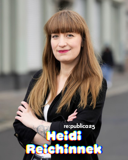 Foto von Heidi Reichinnek. Sie trägt Pony und langes Haar. Mit verschränkten Armen und leichtem Lächeln schaut sie in die Kamera.