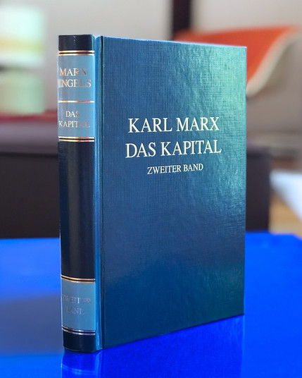 »Das Kapital, Zweiter Band« von Karl Marx, in seiner ikonischen Farbigkeit in Blau und Gold, dreidimensional im Raum fotografiert