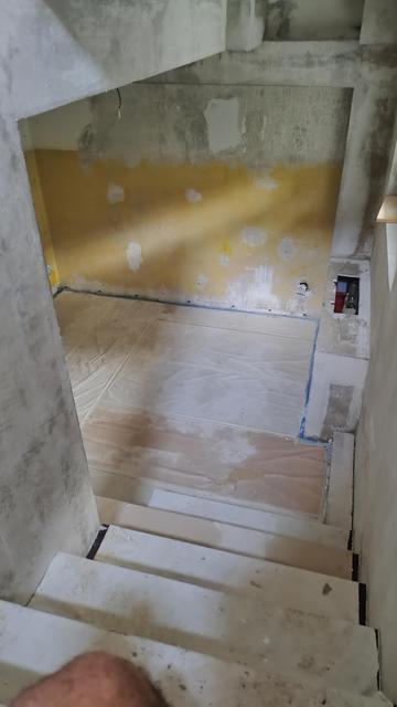 A stairwell and a basement room with patchy walls after I scraped the wallpaper off.