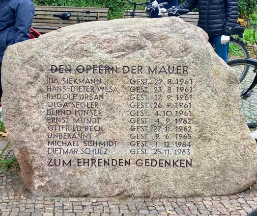 Gedenkstein aus Granit mit der Inschrift „Den Opfern der Mauer“ und einer Liste von zehn Namen mit Sterbedaten, darunter auch ein „Unbekannt“, darunter der Satz „Zum ehrenden Gedenken“.

