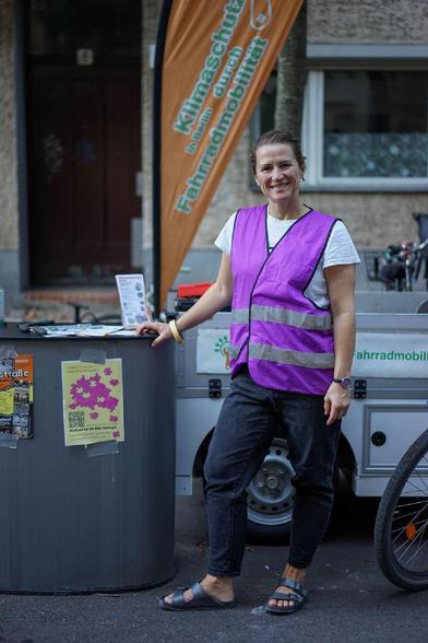 Kinder spielen auf einer für den Verkehr gesperrten Straße im Berliner Stadtteil Wedding bei einer Aktion der temporären Spielstraße; zu sehen sind unter anderem Tischtennis, Laufräder, Straßenmalkreide, Roller und ein großes buntes Schwungtuch.