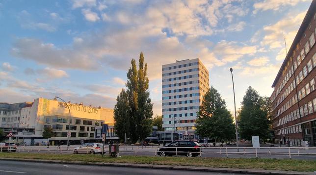 Straßenansicht am Leopoldplatz in Berlin-Wedding mit einem mehrstöckigen Bürogebäude, Bäumen und vorbeifahrenden Autos

