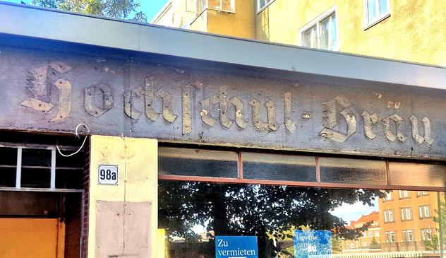 Verwittertes Geschäftsschild mit der Aufschrift „Hochschul-Bräu“ in altdeutscher Schrift über einem leerstehenden Ladenlokal in der Müllerstraße 98a in Berlin-Wedding.

