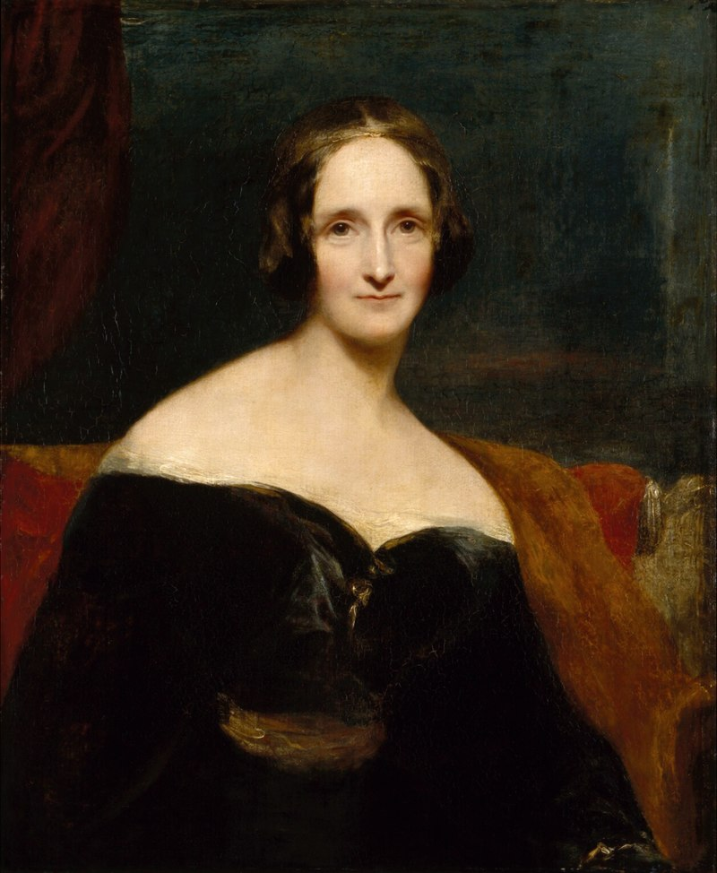 Portrait of Mary Shelley.
A middle aged brunette woman looking intensely directly at the viewer in a dark Victorian dress with bare shoulders