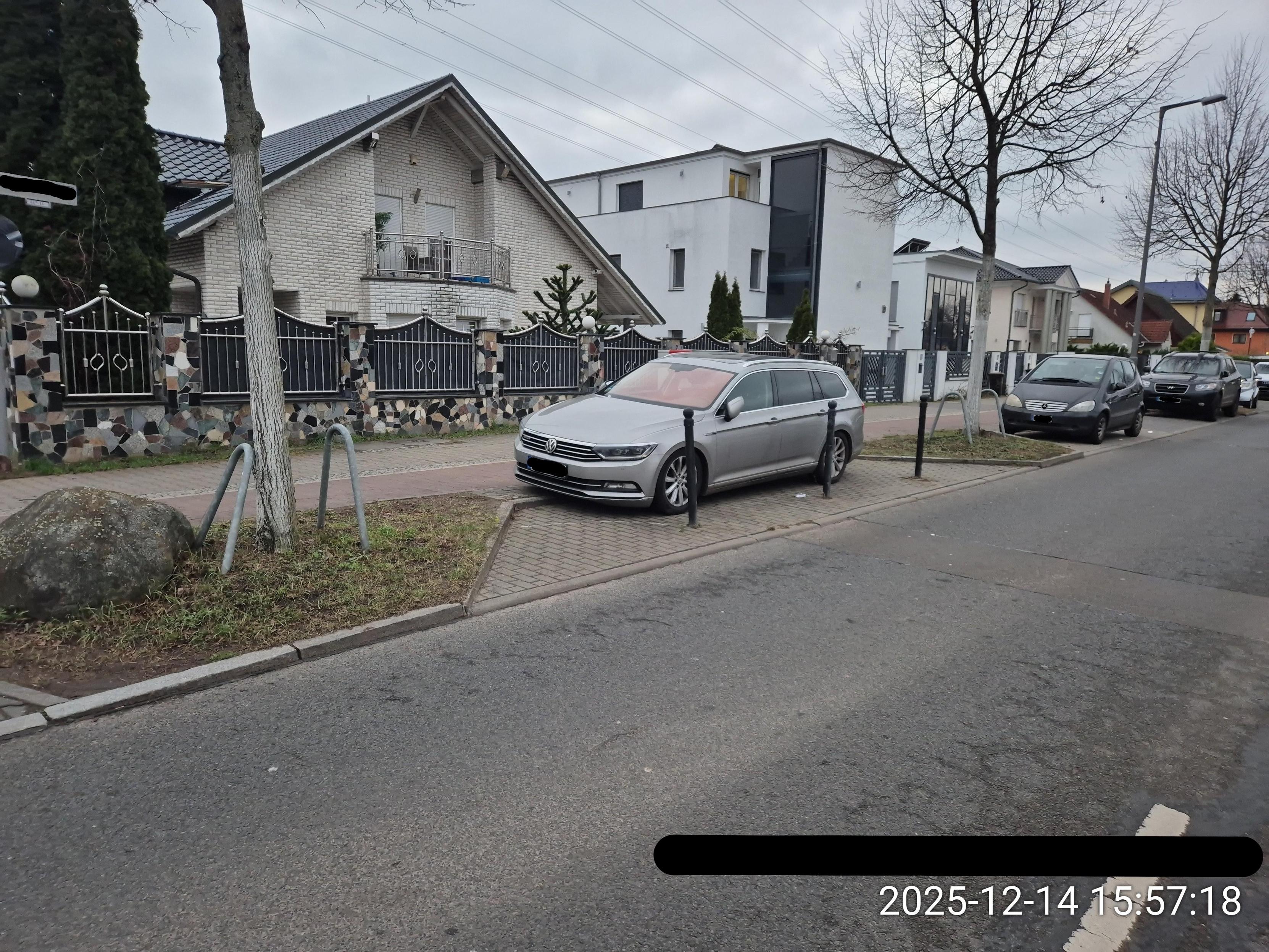 Eine mit drei Pollern gesperrte Parktasche (für genau ein PKW), auf dem ein Auto hinter den Pollern, somit halb auf dem Radweg, steht.